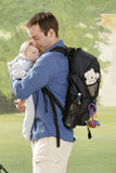 A man holding a baby wearing  A black Alpha Sherpa backpack