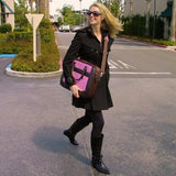 A woman carrying a Pink Suede 16" ScanFast Element Checkpoint Friendly Briefcase w/ Trolley strap for use with rolling luggage, Padded Computer Section, Separate Zippered Workstation, File Sections, Padded Shoulder Strap, Steel Fittings & Faux Leather Wrapped Handles, Exterior Pockets & Matching Detachable Cosmetic Purse