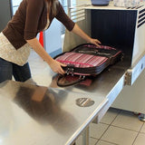 A Pink Suede 16" ScanFast Element Checkpoint Friendly Briefcase w/ Trolley strap for use with rolling luggage, Padded Computer Section, Separate Zippered Workstation, File Sections, Padded Shoulder Strap, Steel Fittings & Faux Leather Wrapped Handles, Exterior Pockets & Matching Detachable Cosmetic Purse opened being put through security x-ray