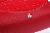 A red Small Sumo Duffel w/ white stitching made of ballistic nylon w/ faux-leather detail, interior pockets, Soft faux-leather shoulder straps, quilted design & printed interior lining.