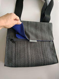 A grey in-flight travel organizer TAB messenger V2 bag w/ black shoulder strap & blue lining.