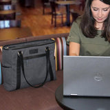 A woman working on a computer in a coffee shop w/ a charcoal 15.6" Urban Laptop Tote w/ black leather trim, handles, & padded computer compartment.